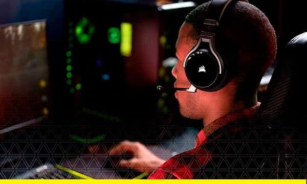 Mies istuu tietokoneen edessä Corsair-pelikuulokkeet päässään