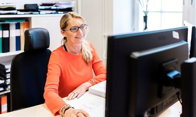 Kvinne sitter foran PC-skjermen sin på kontoret sitt