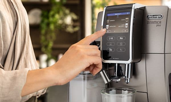 Kvinne som berører displayet på en Delonghi kaffemaskin