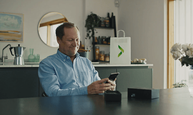 Mann sitter i stue og holder en ny iPhone