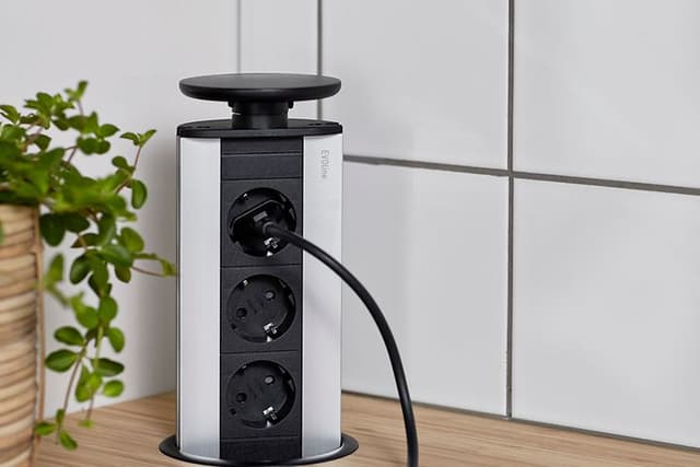 Keittiön työtasoon upotettu EVOLine Port -pistorasia nostettuna ylös ja johon on kytketty musta johto