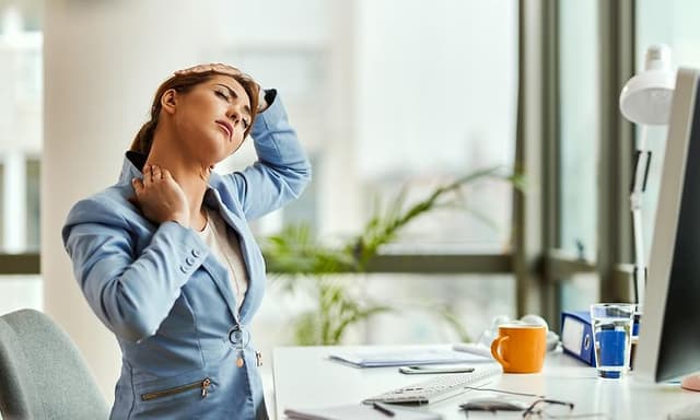 Kvinde strækker sin nakke foran computeren