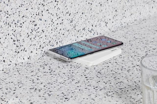 Epoq hvitt EVOLine Square80 stikkontakt med telefon som lader på den på en kjøkkenbenk