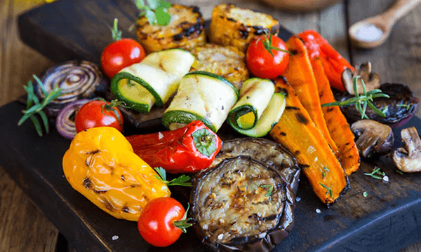 Olika sorters grillade grönsaker på ett svart fat som zuccini, paprika, majs mm.