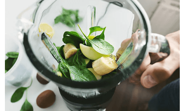 Blender fyldt med skåret frugt og blade