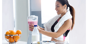 kvinde i sportstøj laver pink smoothie med en blender