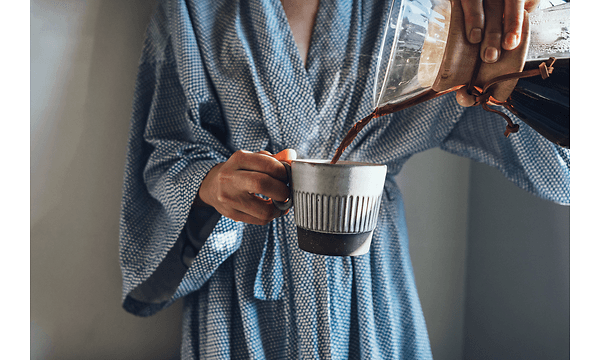 En person I badekåpe heller kaffe opp I en kopp
