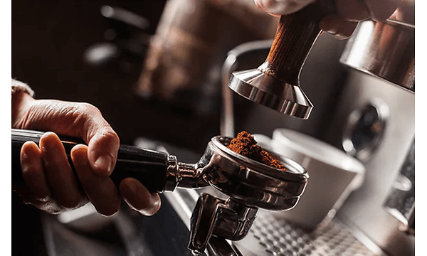 Hånd holder filterholder full av malt kaffe