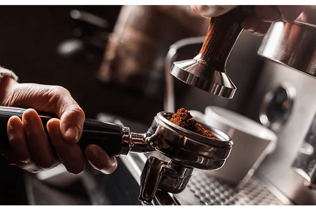 Hånd holder filterholder full av malt kaffe