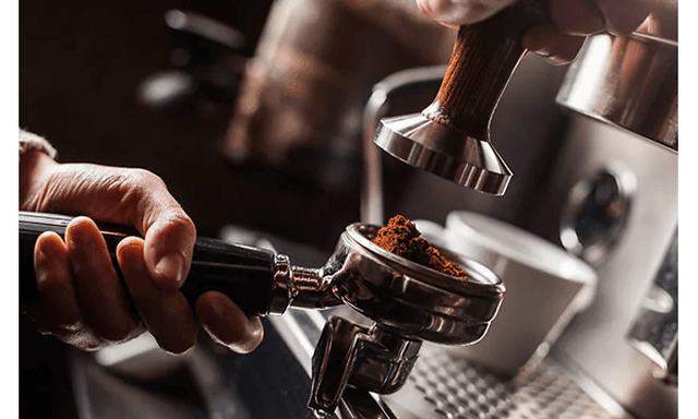 Hånd holder filterholder full av malt kaffe