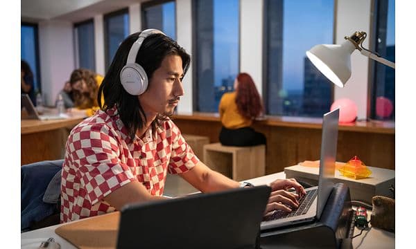 Bose hovedtelefoner - mand med Bose QC45 hovedtelefoner skriver på et kontor