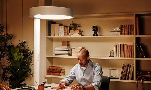 en mann jobber ved et skrivebord med en BrainLit Alven-lampe som lyser opp arbeidsplassen