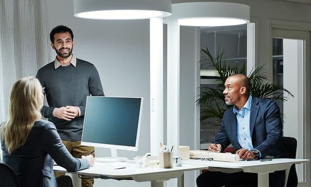 ansatte snakker sammen på et kontor med en brainlit-lampe ved siden av skrivebordet deres