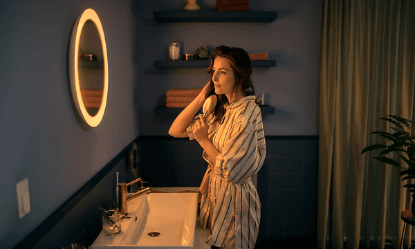 kvinne børster håret sitt foran et Philips Hue Adore-speil