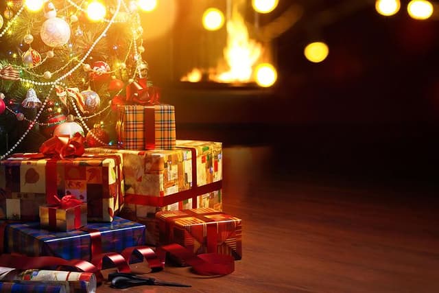 Christmas tree and presents under the tree and a fireplace in the background