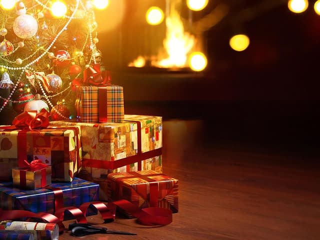 julegaver under et juletre foran en peis