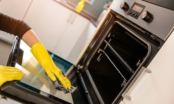 Person rengører fronten på ovnen