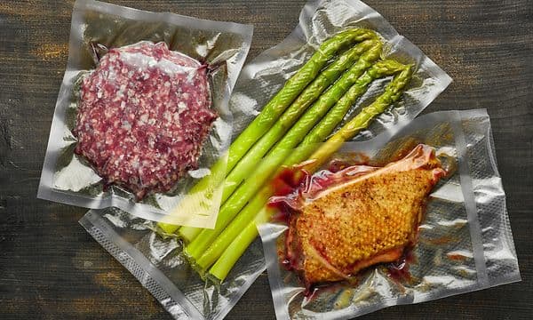 Grøntsager og kød som er vakuumpakket i plastikposer