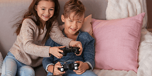 To barn som spiller TV-spill sammen i en sofa