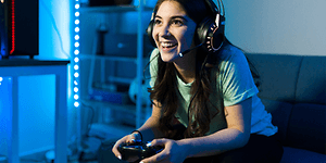 Kvinne med headset som sitter i sofaen og gamer