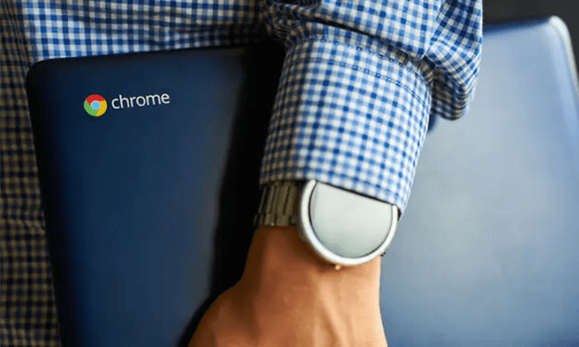 Ruudulliseen paitaan pukeutunut mies pitelee Chromebookia