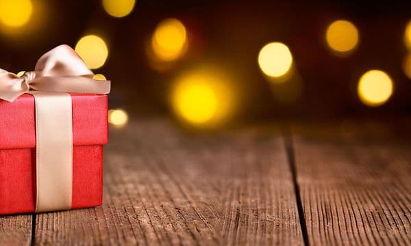 Julklappspel - En röd julklapp med guld rosett mot en mörk bakgrund