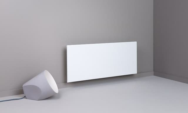 Hvid Adax Neo panelradiator fastspændt til en beigefarvet væg