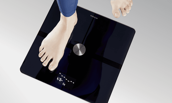 Withings - En kvinde, der står på en Withings smart-vægt
