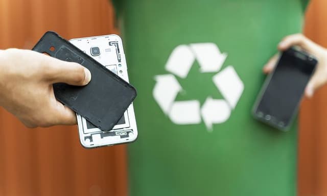 to hender med mobiltelefoner foran en grønn vegg med resirkuleringssymbol