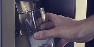 Person fylder et glas vand via en vanddispenser