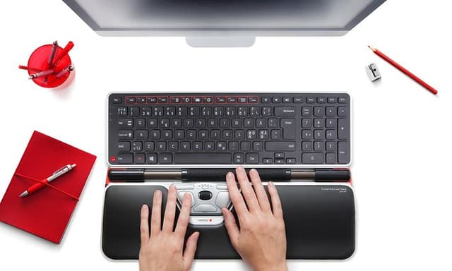 Contour accessories on a white table next to a computer screen and red office supplies
