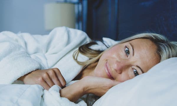 En smilende kvinne som ligger i sengen