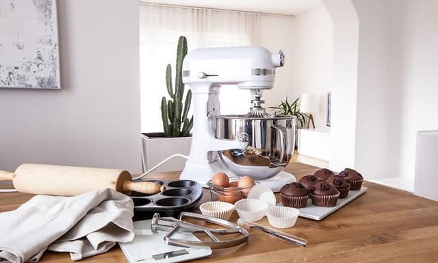 Kjøkkenmaskin på bord med bakeutstyr, muffins og egg