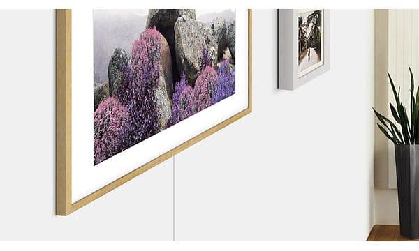 Samsung TV The Frame med konst på skärmen bredvid en bild på en vägg.