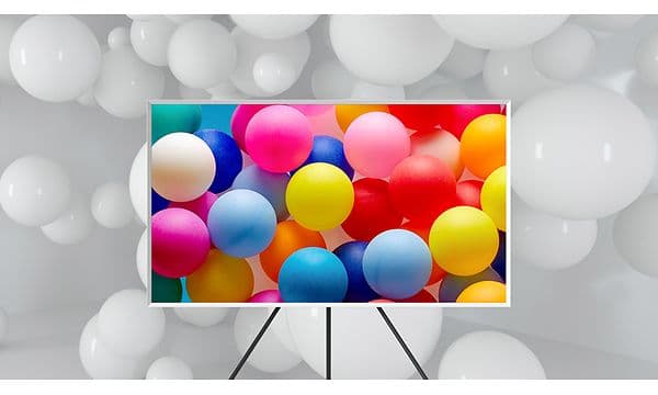 Samsung TV:n The Frame på stativ med färgglada ballonger på skärmen.
