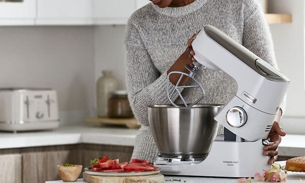 Kvinde løfter overdelen af køkkenmaskinen med K-beater tilbehøret på