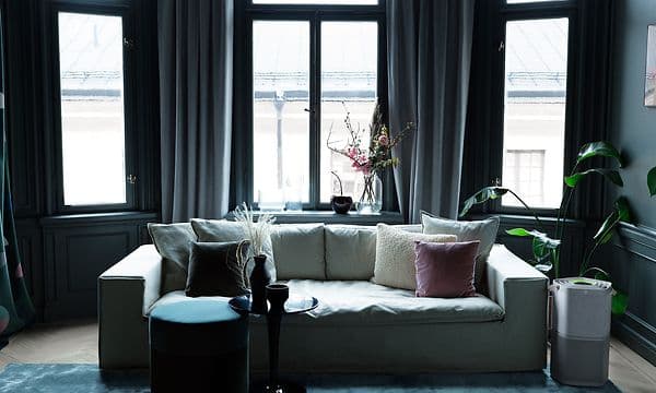 En grå Pure A9 som står ved siden av en hvit sofa i en mørk stue