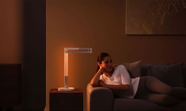 Lightcycle Morph: En kvinna ligger på en soffa bredvid en Dyson-lampa.