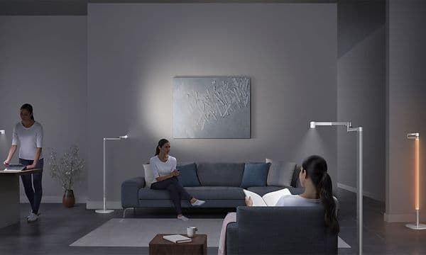 Lightcycle Morph: Samma kvinna på flera ställen i ett vardagsrum med Dyson-ljus.