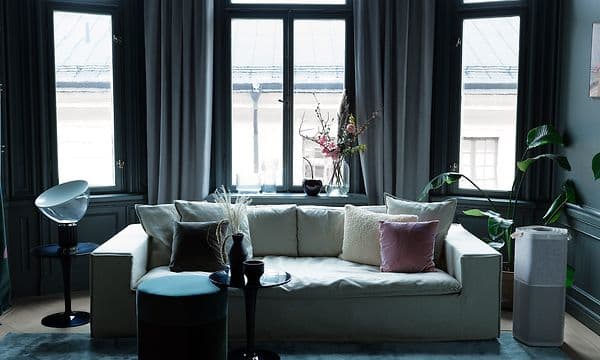 Korkea harmaa Electrolux Pure A9 ilmanpuhdistin vaalean sohvan vieressä tummassa huoneessa