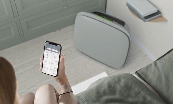 En grå Well A7 på gulvet og en person med Wellbeing-appen på telefonen