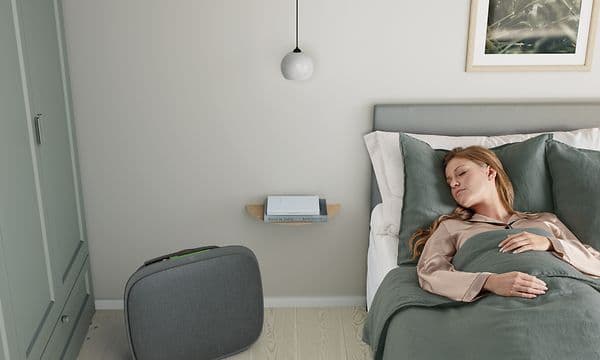 En dame som sover i sengen sin med en mørke grå Well A5 ved siden av seg på gulvet