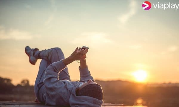 Viaplay - Person ligger på ryggen med mobil