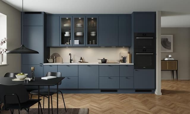 Epoq Trend Blue Grey kjøkken i en åpen kjøkkenløsning med integrert stekeovn, vitrineskap og spisebord