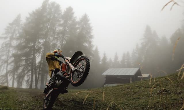 Motocross-pyöräilijä utuisessa maisemassa
