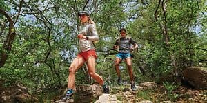 Garmin Fenix 7 på armene på en kvinde og en mand, der løber i vildmarken