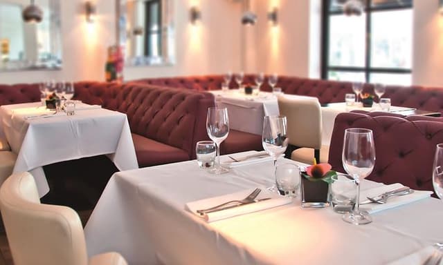 Bord med vit bordsduk i restaurang dukat och klart för gäster