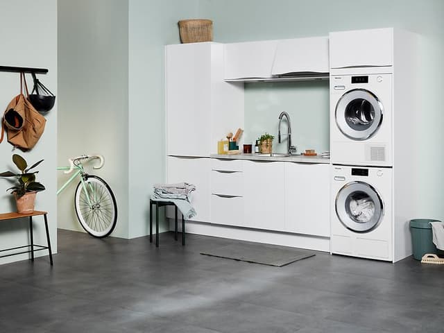 Vit Epoq tvättstuga av serien Gloss White med öppen planlösning i källarlokal med mintgröna väggar.