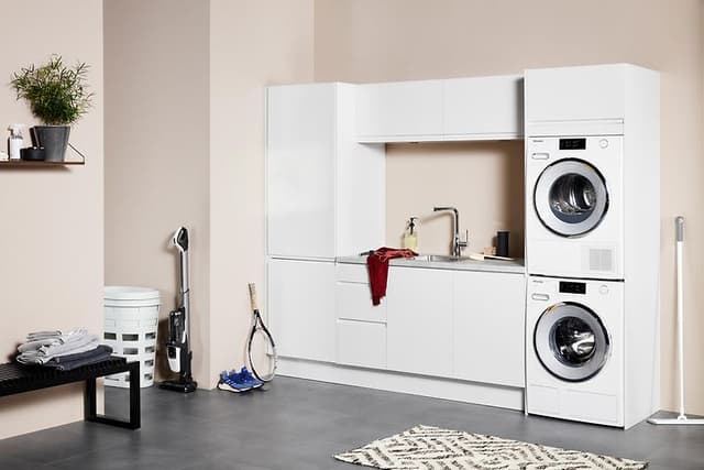 Vit tvättstuga från EPOQ Integra med rosa väggar och tvättmaskin samt torktumlare. 