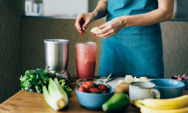 Kvinne som lager en smoothie med banan og jordbær